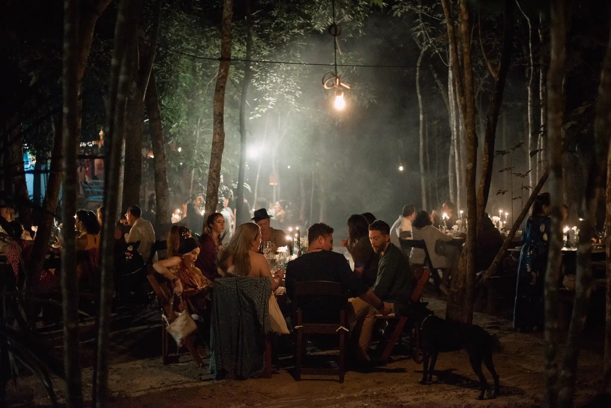 Guests enjoy an intimate wedding Tulum dinner under soft candlelight in a mystical jungle setting.